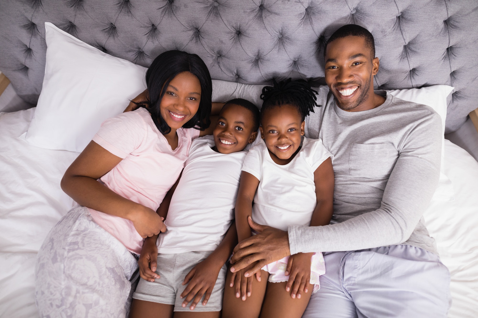 High angle portrait of smiling family lying together on bed