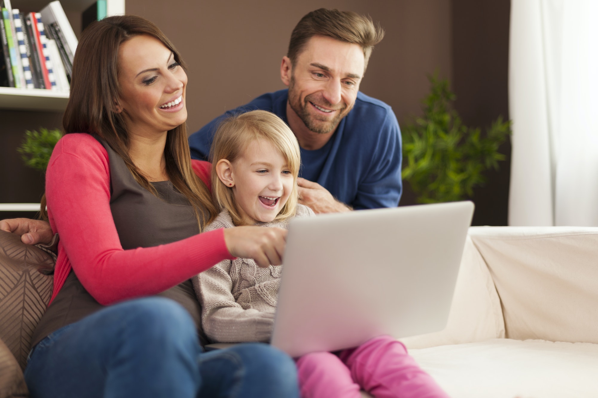 Family laughing together and using laptop at home
